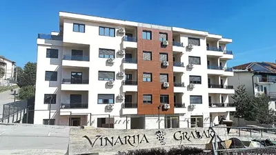 a tall apartment building with a sign in front of it at Apartman Orhideja in Vrnjačka Banja