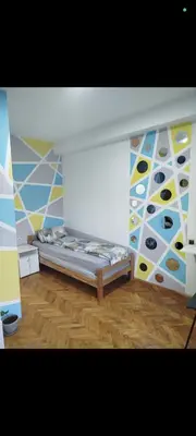 a room with a bed and a wall with paintings at V U Sobe in Brzi Brod