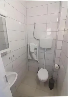 a white bathroom with a toilet and a sink at V U Sobe in Brzi Brod