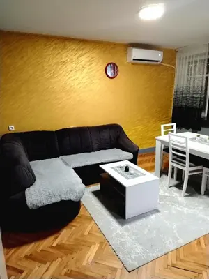 a living room with a black couch and a table at Apartman Zdravković in Leskovac