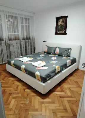 a large bed in a room with a wooden floor at Apartman Zdravković in Leskovac