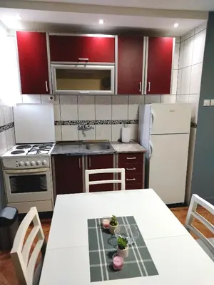 a kitchen with a white table and a white refrigerator at Apartman Zdravković in Leskovac