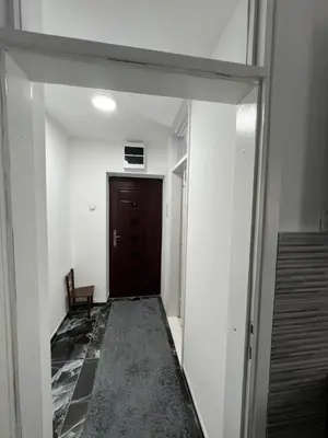 an empty hallway with a door and a chair at Apartman Boža 1 in Kuršumlija