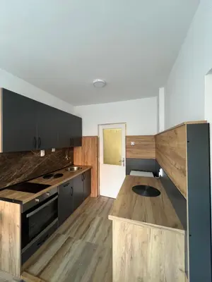 a kitchen with black cabinets and a wooden island at Apartman Boža 2 in Kuršumlija
