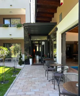 a patio with tables and chairs in front of a building at Vila Pozitiv in Sisevac