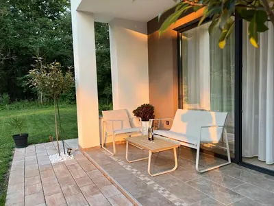 a patio with two white chairs and a table at Vila Pozitiv in Sisevac