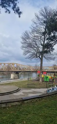 a tree in a park with a bridge in the background at PlavDom2 in Ćuprija