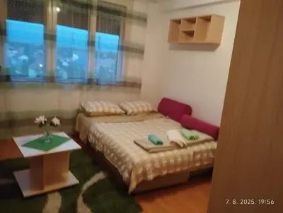a bedroom with a bed and a table and a window at Apartman Krstic in Jagodina