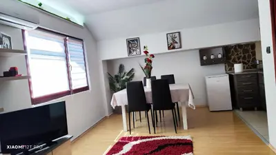 a dining room with a table with chairs and a television at JetNest in Niš