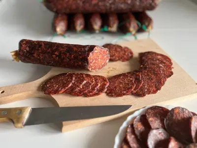 a wooden cutting board with meat and a knife at Travel Rest in Bujanovac