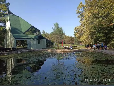 a large pond in a park with a building at Paradise in Lipova in Vrnjačka Banja