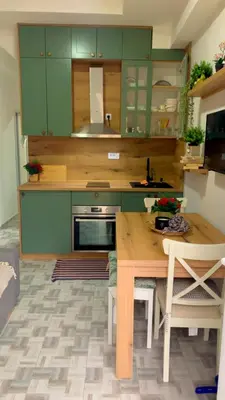 a kitchen with green cabinets and a wooden table at Clementine in Soko Banja