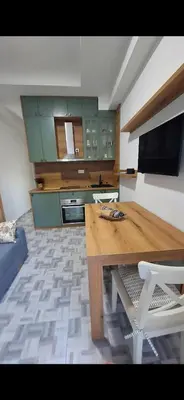 a kitchen with a wooden table and a kitchen with green cabinets at Clementine in Soko Banja