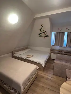 a small bedroom with two beds and a christmas tree on the wall at Apartmani Vrh Konaci in Kopaonik