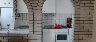 a kitchen with white cabinets and a brick wall at Stamenković in Vranje
