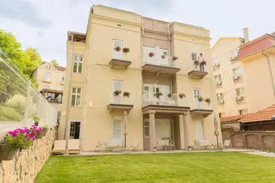 a large yellow building with windows and a yard at Vila Nada Sokobanja in Soko Banja