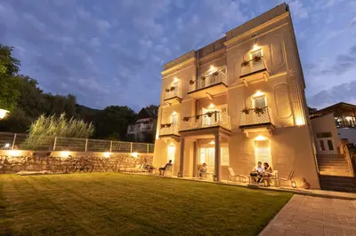 a building with people sitting on a lawn at night at Vila Nada Sokobanja in Soko Banja