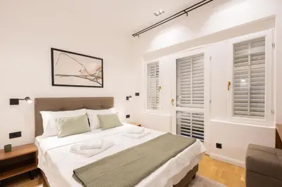 a white bedroom with a large bed and two windows at Vila Nada Sokobanja in Soko Banja