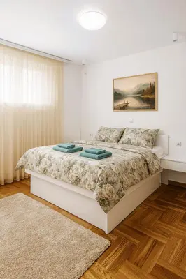 a white bedroom with a large bed with a rug at Luxury Stay in Vrnjačka Banja C2 in Vrnjačka Banja