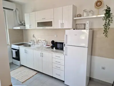 a kitchen with white cabinets and a white refrigerator at Apartman Iris in Pirot