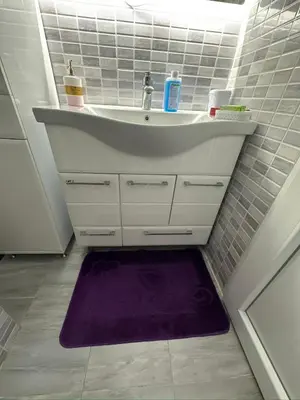 a bathroom with a sink and a purple rug at Smeštaj Versace House
