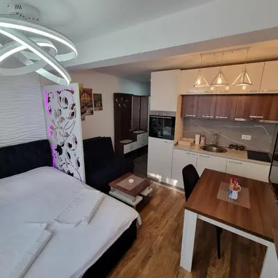 a bedroom with a bed and a table and a kitchen at Apartman President Kop in Kopaonik
