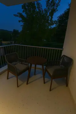 two chairs and a table on a balcony at night at Luxury Stay in Vrnjačka Banja D3 in Vrnjačka Banja