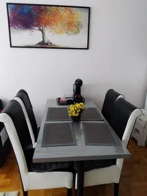 a dining room table with chairs and a painting on the wall at Studio apartman BB4 in Vrnjačka Banja