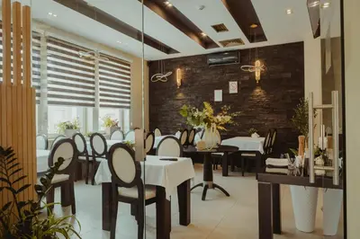 a dining room with tables and chairs and a brick wall at Garni Hotel Biser in Kruševac