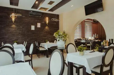 a restaurant with white tables and chairs and a brick wall at Garni Hotel Biser in Kruševac
