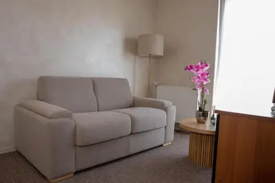 a living room with a couch and a table with flowers at Garni Hotel Biser in Kruševac