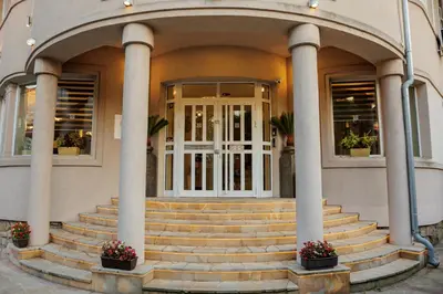 a building with pillars and stairs in front of a door at Garni Hotel Biser in Kruševac