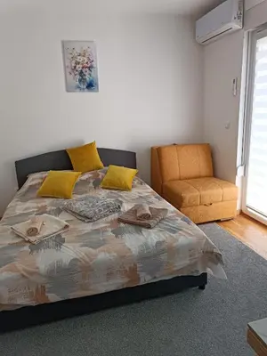 a bedroom with a large bed and a chair at Lipa in Vrnjačka Banja