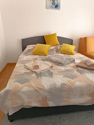 a bed with two yellow pillows and a bedspread at Lipa in Vrnjačka Banja