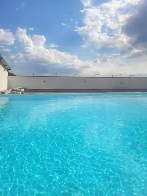 a swimming pool with blue water in front of a building at Diamona Lux Apartman 1 in Donja Toponica