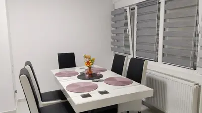 a dining room table with chairs and a white table with flowers on it at Lela's home II in Knjazevac.