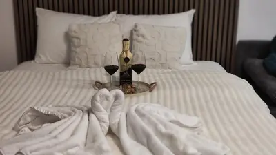 a bed with a bottle of wine and two glasses at SKY VIEW Apartment - Ski resort Kopaonik in Cajetina