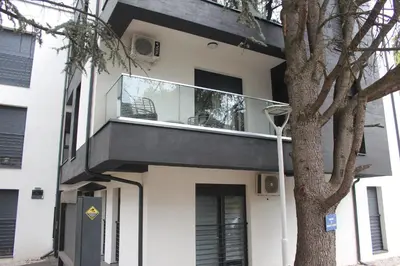 a house with a balcony and a tree at Apartment Ornament Lux B11 in Vrnjačka Banja