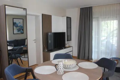 a living room with a table with chairs and a television at Apartment Ornament Lux B11 in Vrnjačka Banja