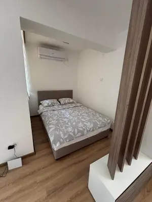 a bedroom with a bed in a room with wooden floors at Apartman A2 in Vrnjačka Banja