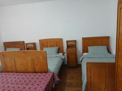 a room with three beds and a table in it at KAMENICA Stara Planina in Dimitrovgrad