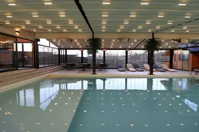 a swimming pool with chairs and trees in a building at Skyline Panorama in Vrnjačka Banja