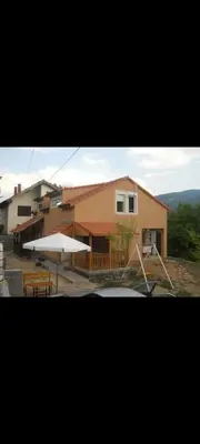 a house with a table and an umbrella in front of it at Smeštaj Miok in Soko Banja