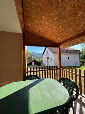 a green table and chairs on a porch with a fence at Smeštaj Miok in Soko Banja