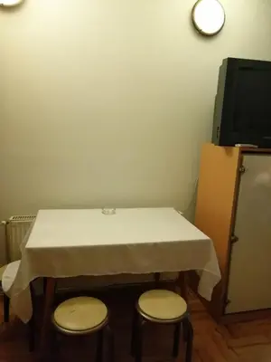 a table with two stools in a room with a television at Pansion Velickovic in Niška Banja