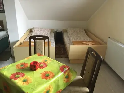 a room with two beds and a table and chairs at Pansion Velickovic in Niška Banja