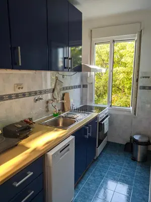 a kitchen with blue cabinets and a sink and a window at Golden lady in Niš