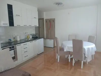 a kitchen with a table and chairs and white cabinets at Apartmani Vrnjacka Banja in Vrnjci