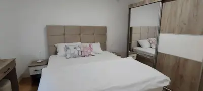 a bedroom with a large white bed and a mirror at Apartmani Vrnjacka Banja in Vrnjci