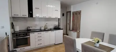 a kitchen with white cabinets and a table and a table sidx sidx sidx at Apartmani Vrnjacka Banja in Vrnjci